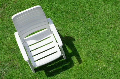 High angle view of empty bench on grassy field