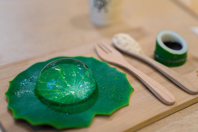 Close-up of leaf with drop on cutting board over table