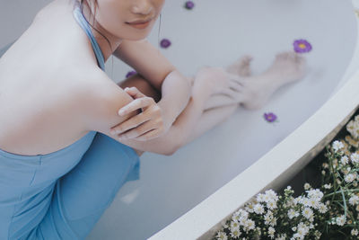 Low section of young woman relaxing in bathtub