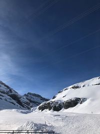 Scenic view of snow covered mountains against blue sky