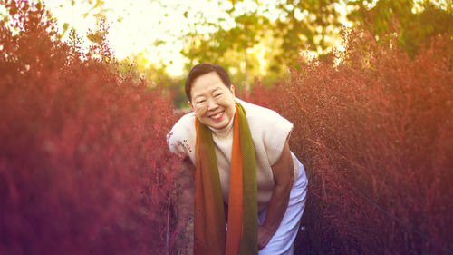 Happy woman standing by tree against plants