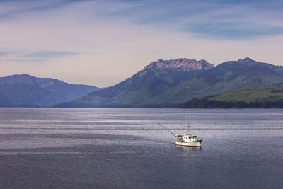 Sailboat sailing on sea against mountains