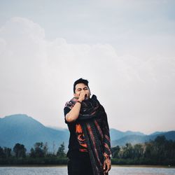 Young woman standing by lake against mountains