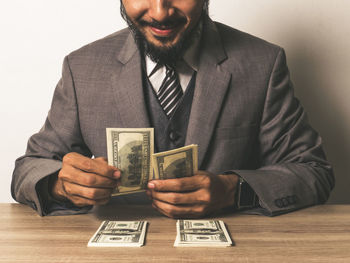 Midsection of businessman with paper currency at table