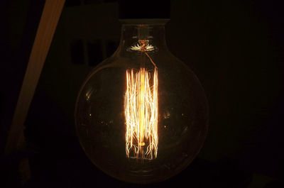 Close-up of illuminated light bulb against black background