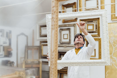 Carpenter examining frames in woodshop