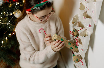 A girl takes out gifts from a wall advent calendar.