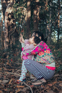 Mother with daughter gesturing against trees in forest