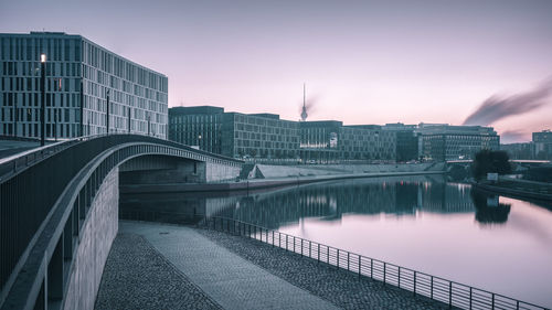 Buildings by canal in city at dusk