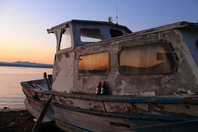 Abandoned boat on beach against sky during sunset 