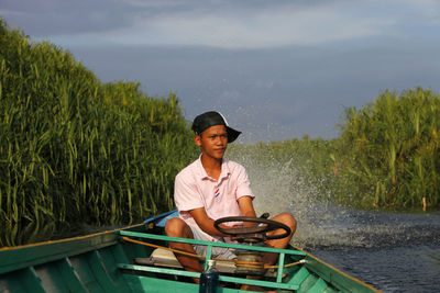 Man sitting in boat against plants