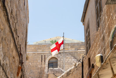 Low angle view of flag amidst buildings against clear sky