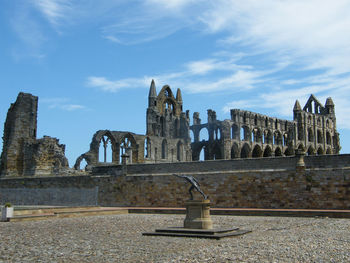 Statue at whitby abbey against cloudy sky