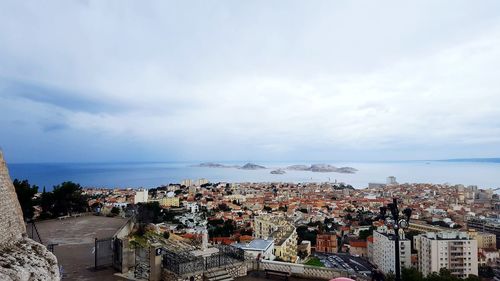 High angle view of town by sea against sky