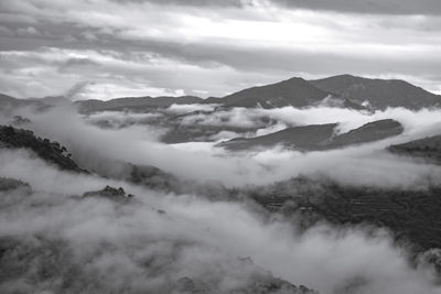 Scenic view of fog covered mountains against sky