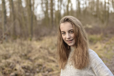 Close-up portrait of teenage girl smiling in forest