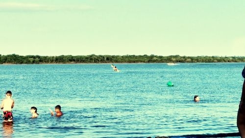 People enjoying on sea against sky