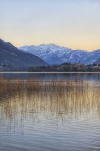 Scenic view of lake by snowcapped mountains against sky