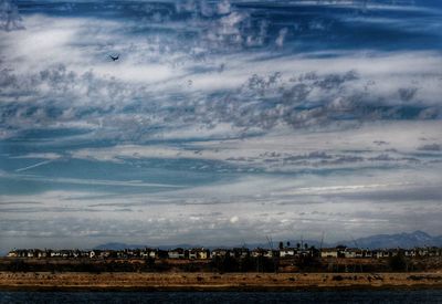 Distant view of city against cloudy sky