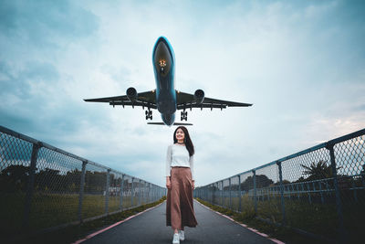 Low angle view of woman standing on airplane against sky