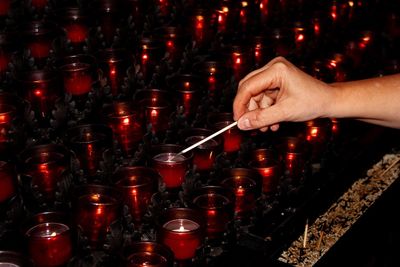 Midsection of person holding illuminated candles in temple