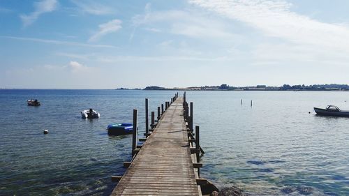 Pier over lake against sky with boats