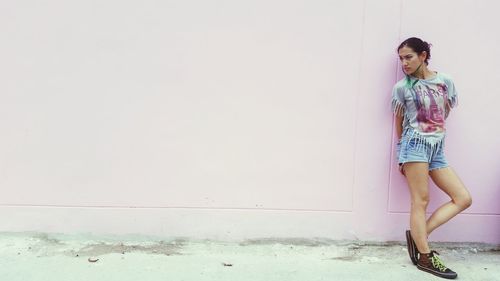 Young woman standing against wall