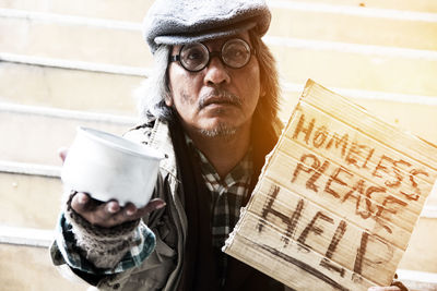 Portrait of beggar with text and bowl sitting on steps