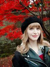 Portrait of smiling young woman standing against trees