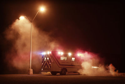 Vehicles on road against sky at night