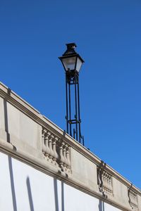 Low angle view of street light on building terrace against clear blue sky