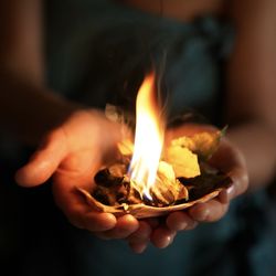 Close-up of hand holding burning candle