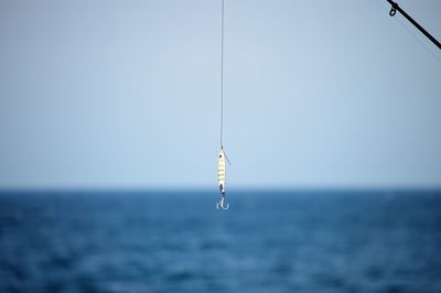 Fishing rod on sea against clear sky