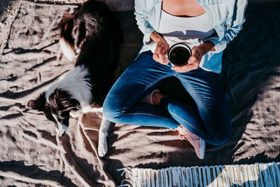 Low section of woman with dog sitting on blanket