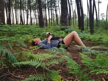 Full length of woman lying on field at forest