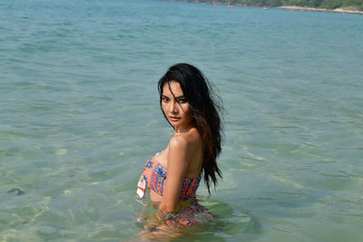 Portrait of young woman posing in sea at beach