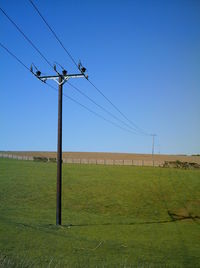 Electricity pylon on field against clear sky