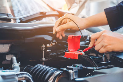 Cropped hands of mechanic repairing car in garage