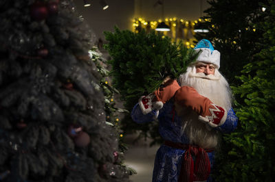 Portrait of woman standing by christmas tree