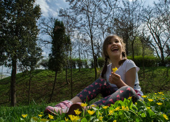 Smiling boy sitting on land against trees