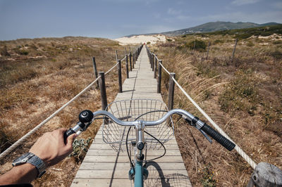 Close-up of man riding bicycle on footbridge at mountain 