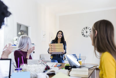 Young women bringing pizza for friends studying at home