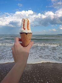 Midsection of person holding ice cream on beach