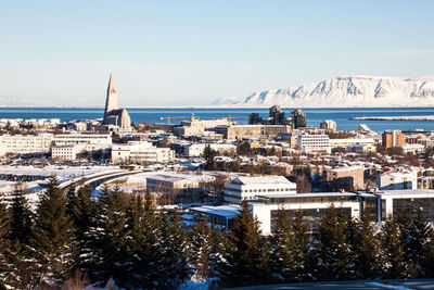 Aerial view of city by sea against sky