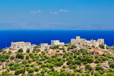 Buildings by sea against blue sky