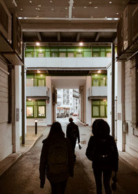 Rear view of people walking through arch under building