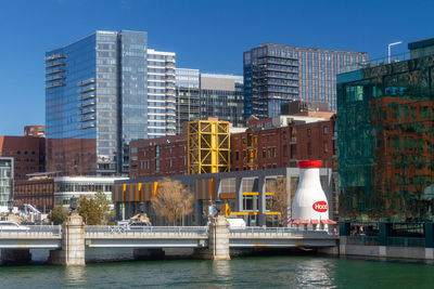 Modern buildings by river against sky in city