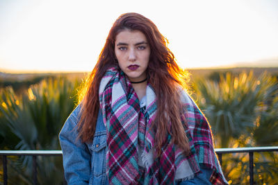 Portrait of beautiful young woman standing against clear sky