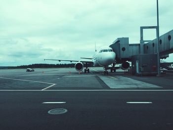 Airplane on airport runway against sky