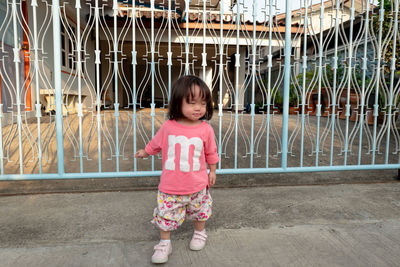 Girl standing against metallic gate 